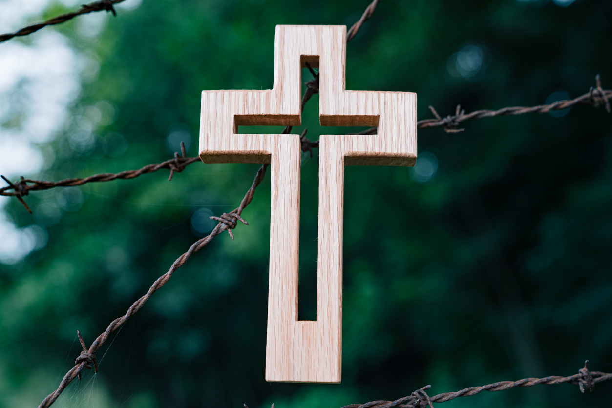 Kreuz hängt auf Stacheldraht.